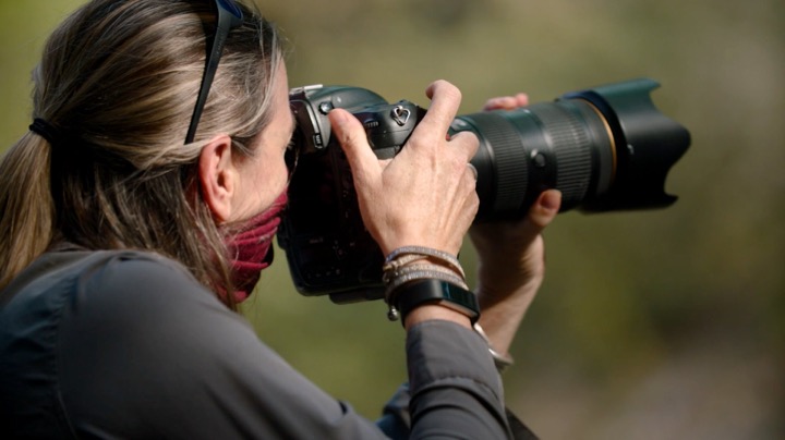 Photographer aiming a long camera lens outdoors